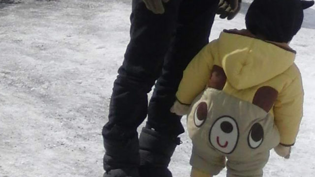 クマのスノーウェアを着た子供の後ろ姿